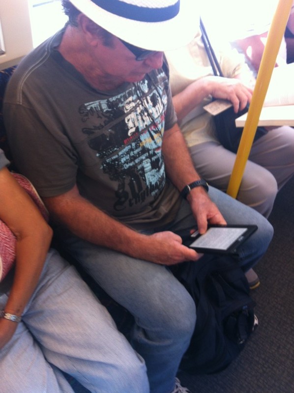 Pessoa lendo no kindle, no trem, em Perth