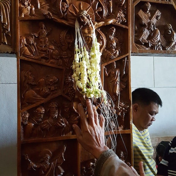 Colar de sampaguita, a flor típica filipina, é depositado sobre a cruz