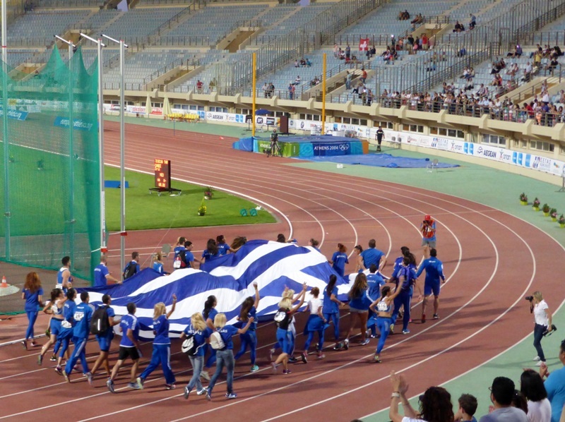 Atletas carregando a bandeira da Grécia, no Campeonato Europeu de Atletismo, em Heraklion